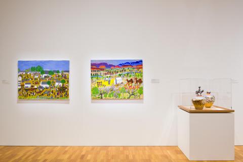 An installation view of paintings and ceramic pots installed in a bright gallery space