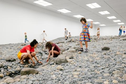 A view of young gallery visitors exploring Olafur Eliasson's 'Riverbed' installation, inside a bright gallery space