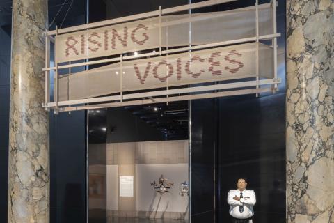 'Rising Voices' at the Victoria and Albert (V&A) Museum, London, May 2025, guarded by Michael Parekōwhai's Kapa Haka (Whero) 2003, and with glimpses of headdresses by Ken Thaiday Snr / © The artists / Image courtesy and © The V&A, South Kensington