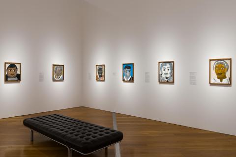 Six portraits by Heather Marie (Wunjarra) Koowootha, installed across two walls in a gallery space, with a bench in the foreground
