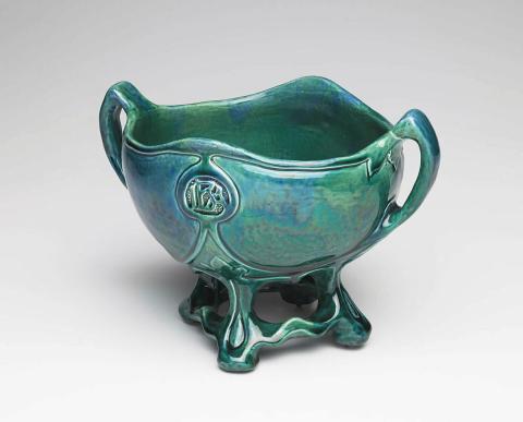 Artwork Footed bowl with handles this artwork made of Earthenware, hand built with carved decoration and glazed blue/green, created in 1925-01-01