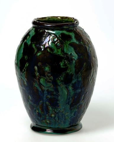 Artwork Vase this artwork made of Earthenware, hand-built white clay dipped brown and carved with a design of grape leaves, fruit, tendrils and insects.  Glazed blue/green, created in 1927-01-01