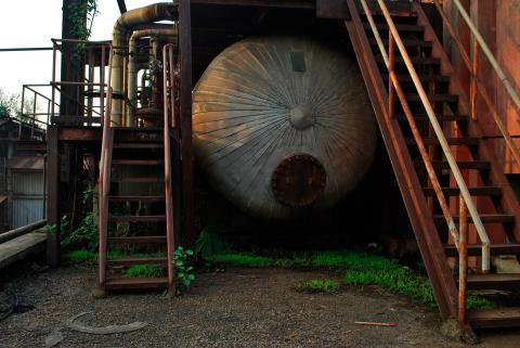 A still photo of an industrial tank with rusted stairways either side.