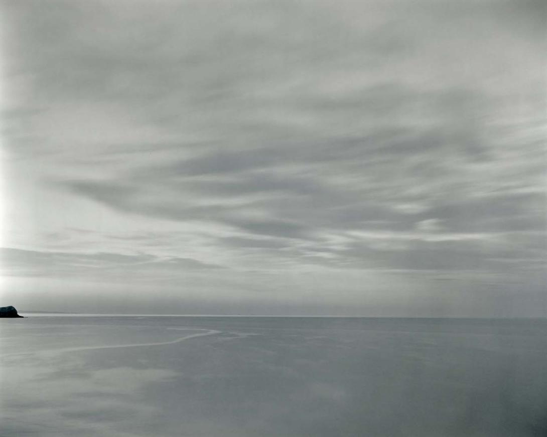 A greyscale photo of the ocean, with the horizon line about two-thirds of the way down the composition.