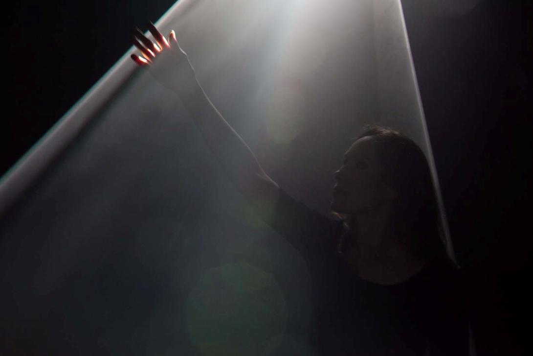 An installation view of a visitor exploring a work made of light.