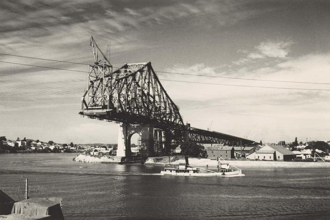 A black-and-white photograph of a bridge mid-construction