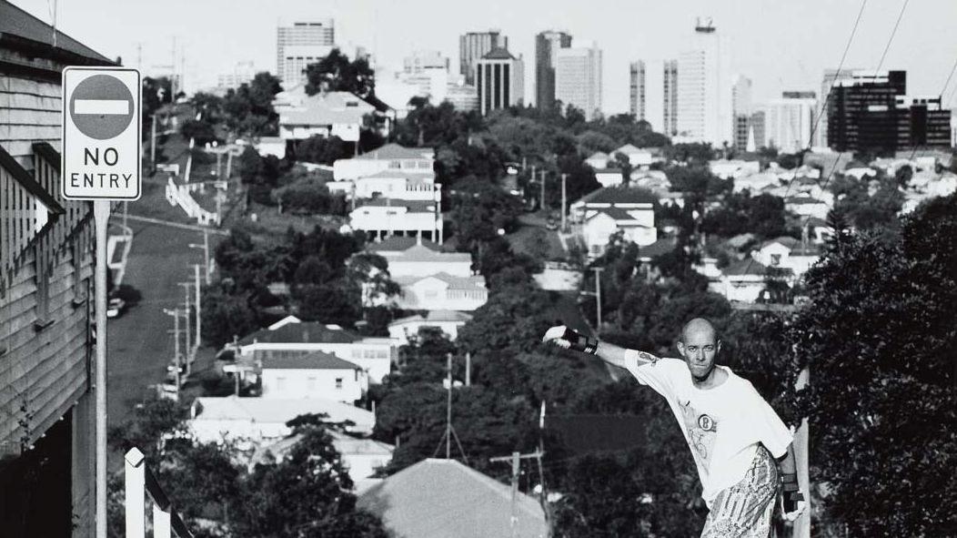 Detail view of a black-and-white photograph of a Brisbane suburb with a skateboarder in the foreground