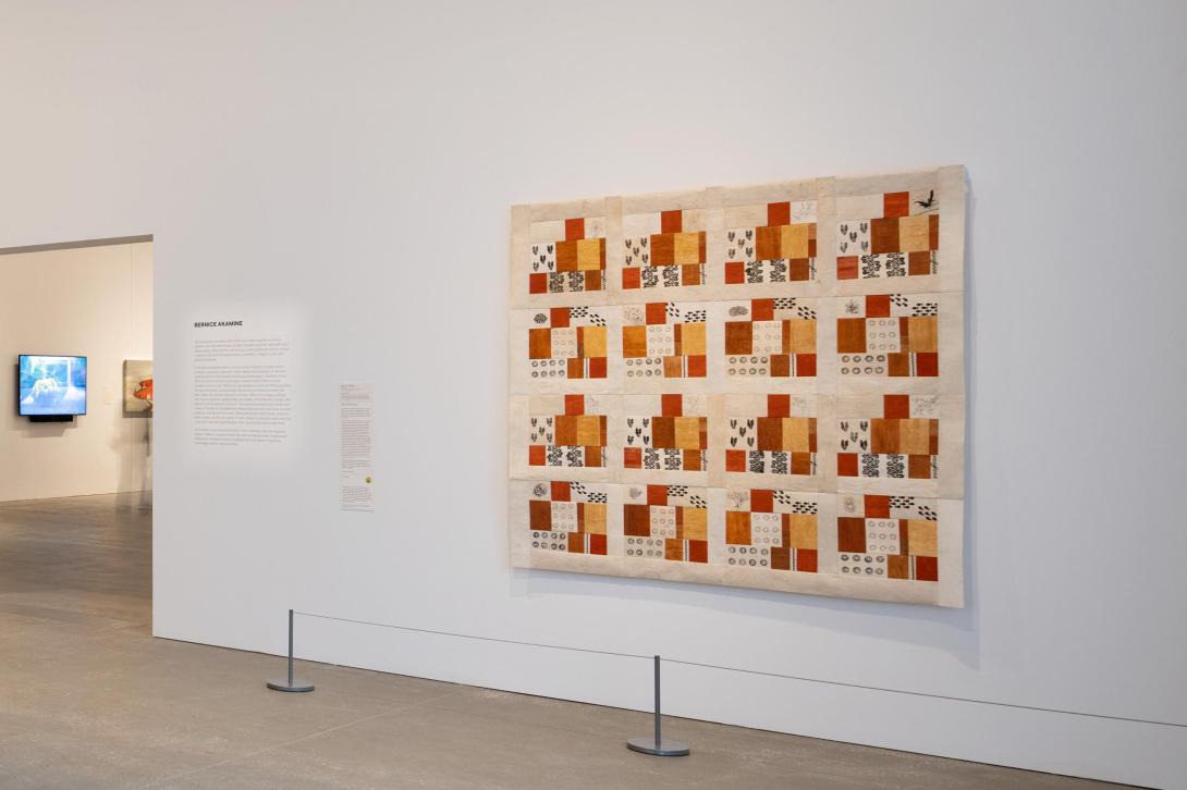 A quilted work installed on a wall in a gallery space.