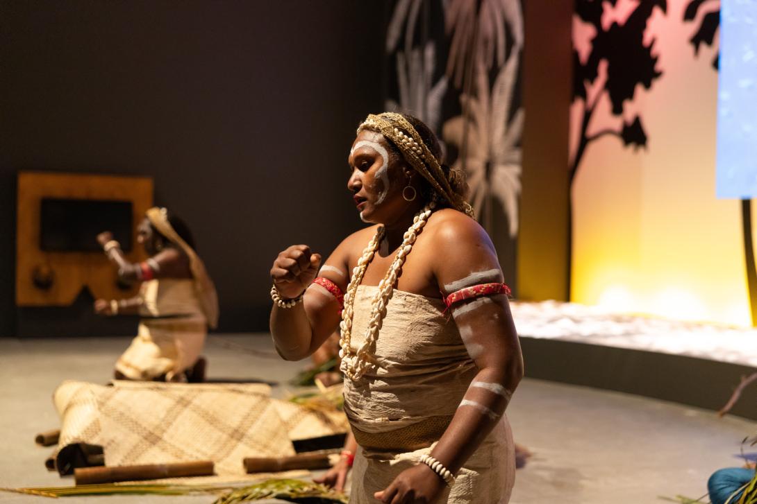 A performance by Solomon Islands artists within a colourfully lit gallery space