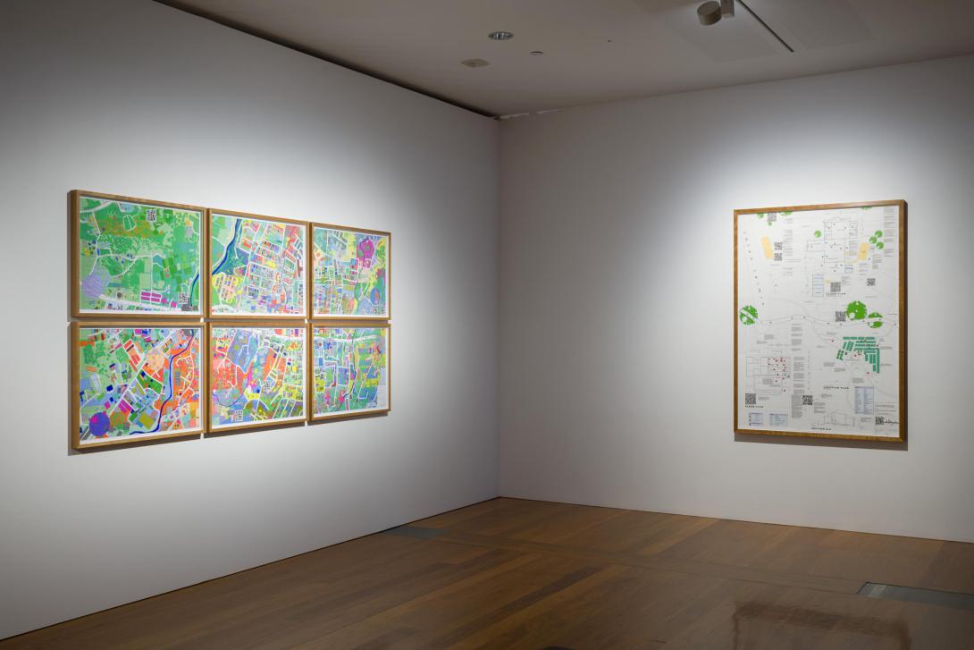 Two colourful map-like artworks installed in a gallery space