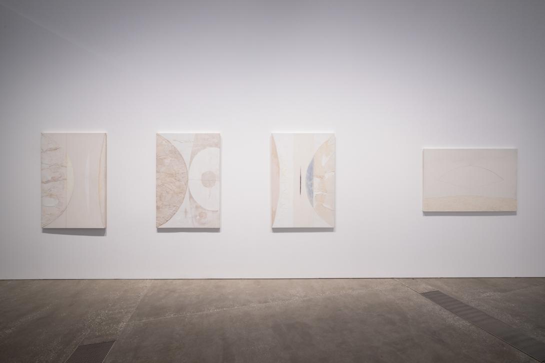 Four very pale coloured artworks installed on a white gallery wall
