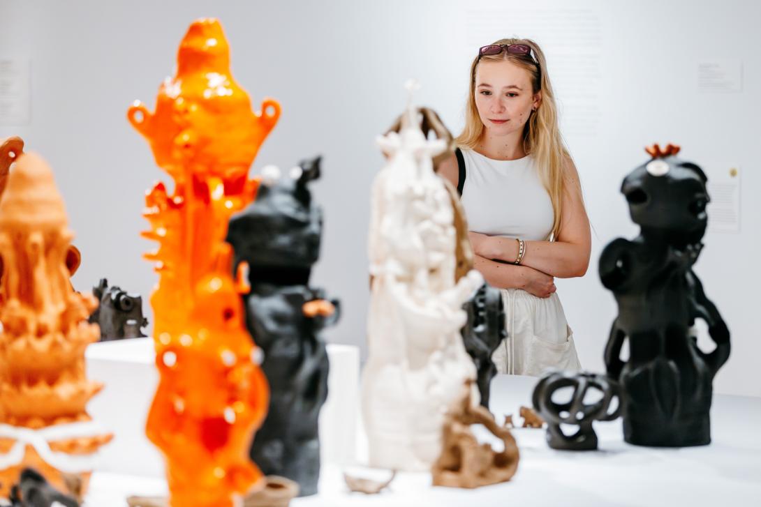 A detail view of grotesque clay sculptures in bright orange and earth tones