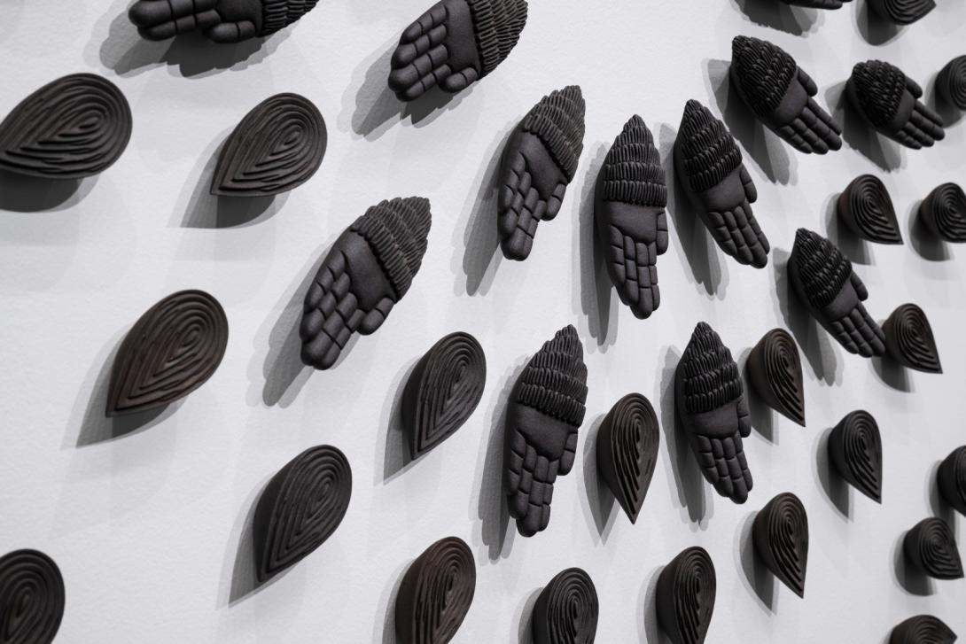 Ceramic hands installed in a radiating pattern on a gallery wall
