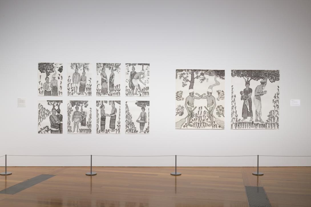 A view of eight smaller and two larger works in black ink on white paper installed on a white gallery wall