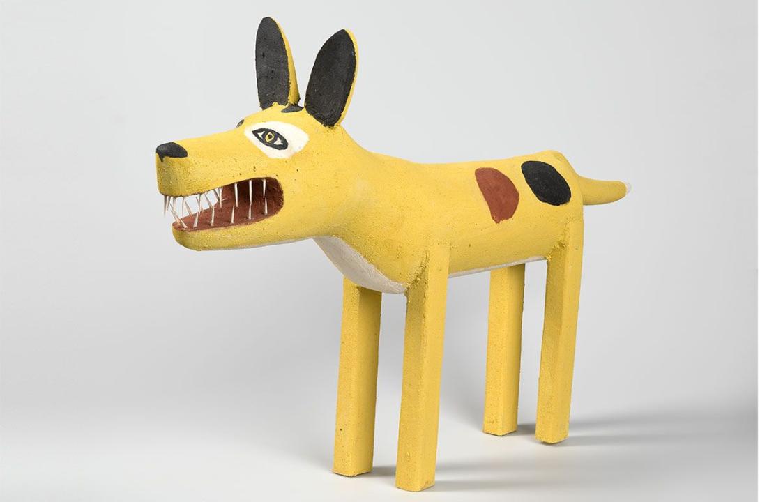 An installation view of a bright yellow sculpture of a domestic dog
