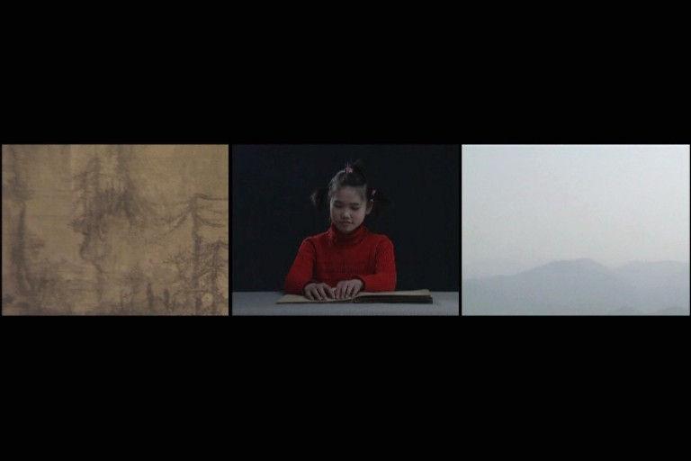 In this still from a three-channel, colour video work, three screens are visible. The central screen shows a young girl, wearing red, reading braille. The left-hand screen shows a detail view of a scroll painting called Early Spring 1072, by renowned Song-dynasty artist Guo Xi. The right-hand screen shows a landscape of tall fir trees and open skies.