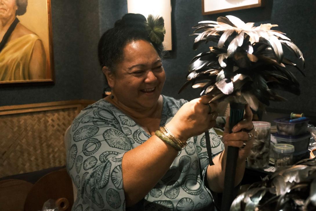 A photograph of a Hawaiian artist in her studio creating a feather standard for an Asia Pacific Triennial installation
