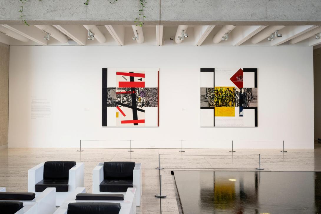 A gallery display of two large, colourful, square-shaped paintings installed on a bright white wall, with a pool of water and chairs in the foreground. 