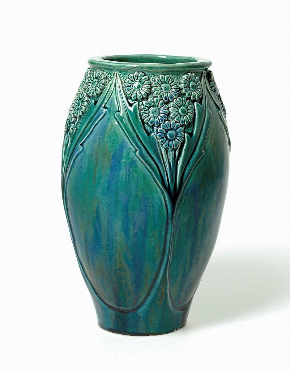 Artwork Daisy vase this artwork made of Earthenware, hand-built swelling cylindrical form carved with daisy and leaf motif, glazed green and blue, created in 1930-01-01