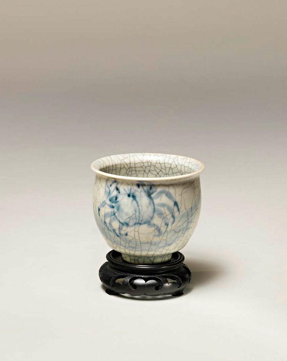 Artwork Tea bowl with crab motif this artwork made of Porcelain, wheelthrown with brushed cobalt decoration and crackled celadon glaze with wooden stand, created in 1970-01-01