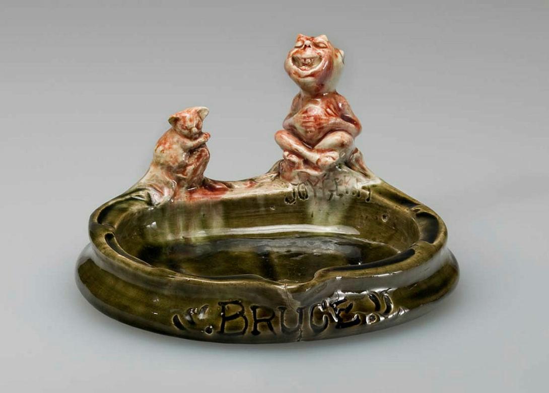 Artwork Porridge plate with 'Joy germ': Bruce this artwork made of Earthenware, modelled lip applied with a pink koala and a figure of an imp. Olive green glaze, created in 1937-01-01