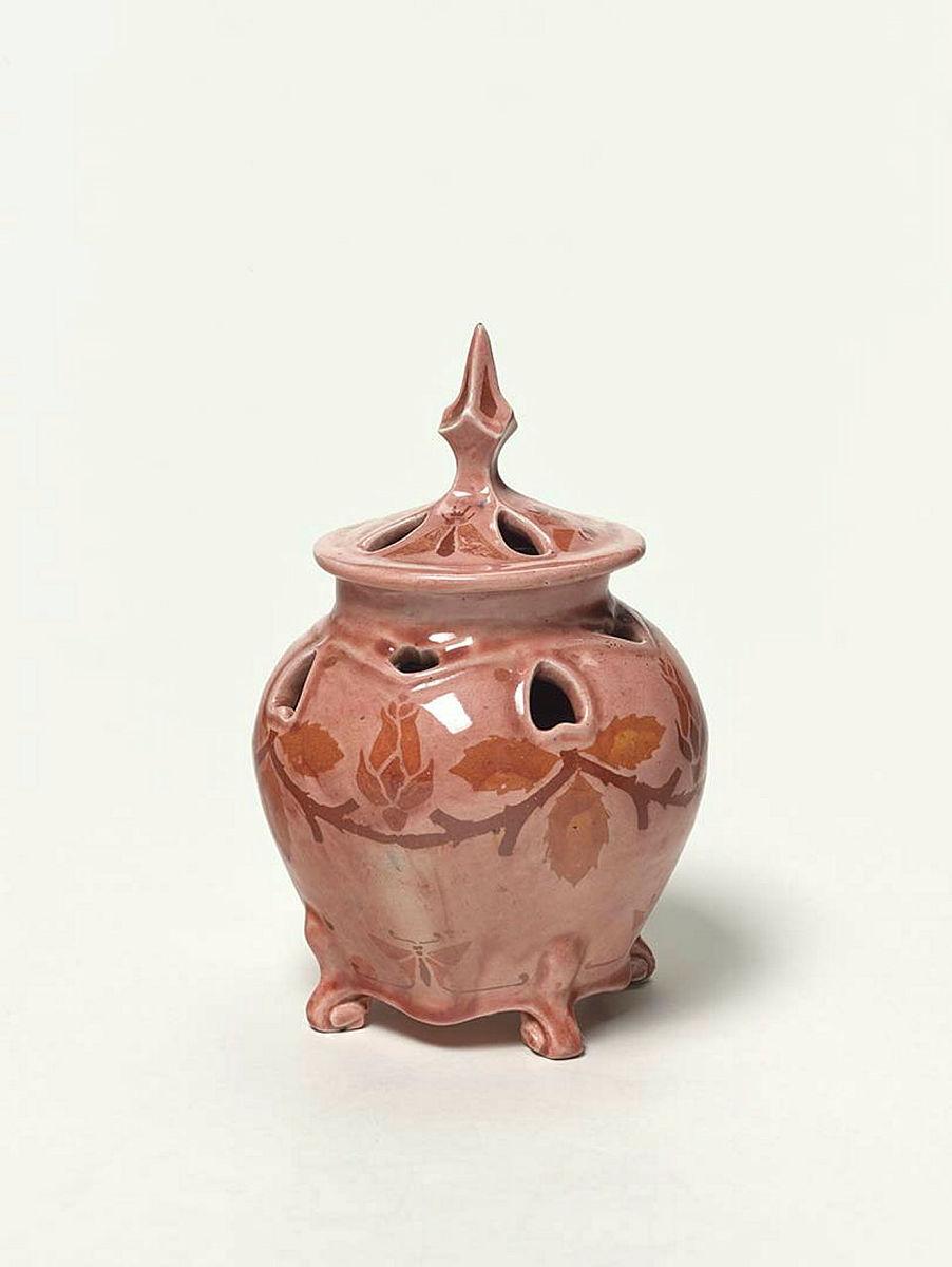 Artwork Large potpourri this artwork made of Earthenware, hand built and inlaid with rosebuds and a swag under a rose-coloured glaze. Prominent peaked lid, created in 1920-01-01