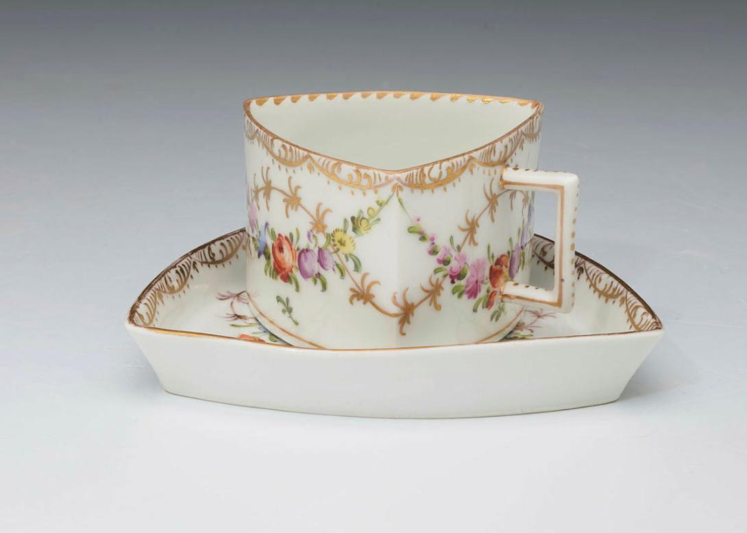 Artwork Triangular cup and saucer this artwork made of White porcelain body with gilt scalloped and dentil rim and pendant polychromed swags of flowers, created in 1840-01-01