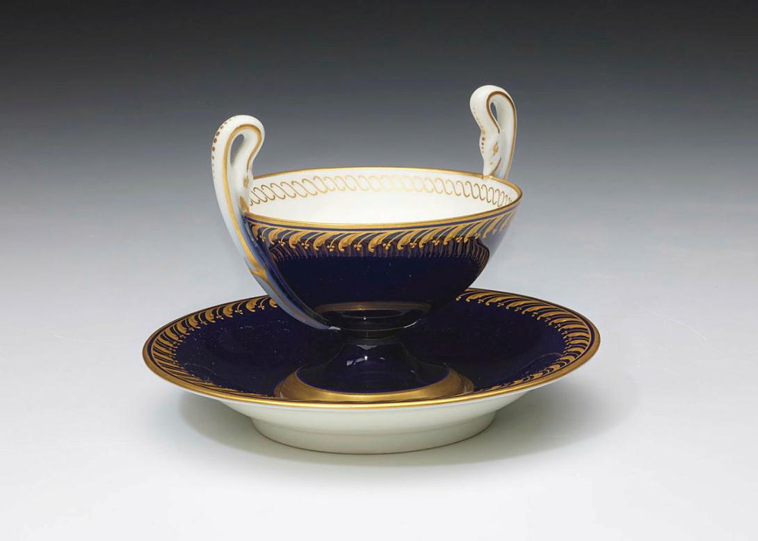 Artwork Kylix shaped cup and saucer this artwork made of Hard-paste porcelain kylix shape with deep cobalt body with feathered gilt borders.  Gilt foot to cup and interior rope rim, created in 1890-01-01