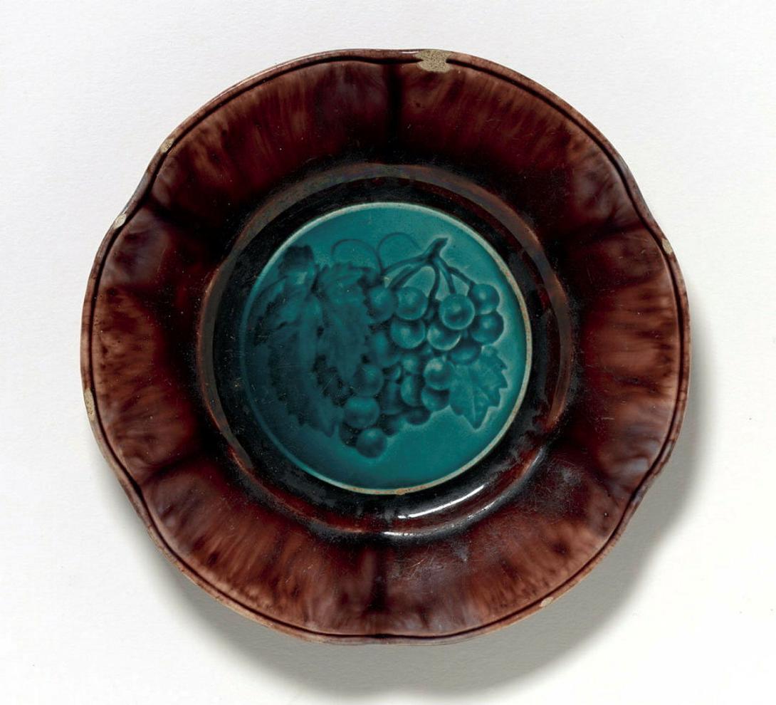 Artwork Plate this artwork made of Earthenware the well impressed with a design of grapes and glazed blue with tortoiseshell glazed rim, created in 1836-01-01