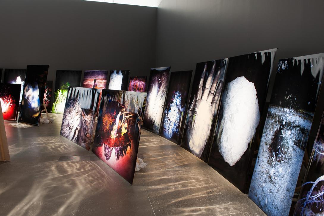 An installation view of a gallery space with many large-scale artworks on canvas propped up in rows on the floor, rather than the walls.