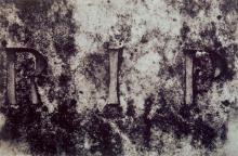 A black and white photograph of 'R.I.P' written on a gravestone