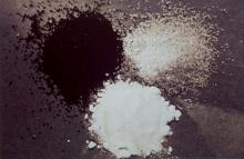 A black and white photograph of three powdered pigments in piles