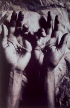 A black and white photograph of hands with stigmata