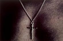A black and white photograph of masculine chest wearing a crucifix on a chain