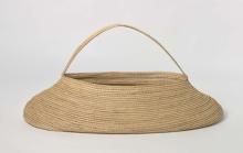 A golden-yellow basket just over a metre in length made from coil-woven sedge rushes