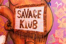 A detail view of an installation: this photograph depicts a sign that says SAVAGE KLUB in chunky text.