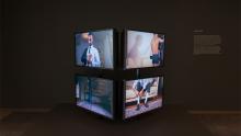 An installation view of a video work presented across four screens.