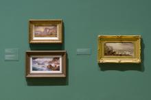 An installation view of three oil paintings installed on a sage-green wall.