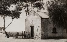 A black and white photograph of a small building in a desert setting.