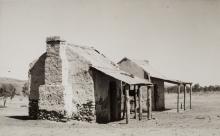 A black and white photograph of small buildings in a desert setting.