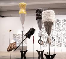 Textile works installed in the centre of a gallery space, with other artworks installed on walls behind