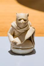 A photograph of a tiny, 5cm-tall tanuki, disguised as a priest, carved from ivory.
