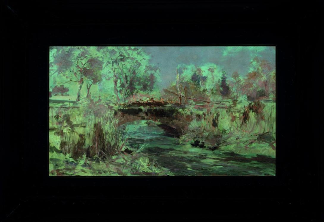 A framed oil painting of a small creek and a bridge, called 'Misty Morn' by Tom Roberts photographed in UV light