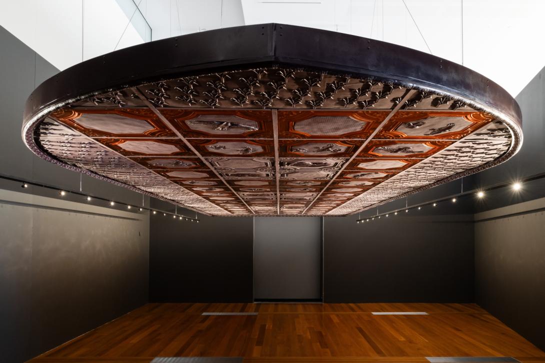 A view of a large installation shaped like a ship and suspended from the ceiling, giving the viewer the impression they are standing in the 'hold' of the ship
