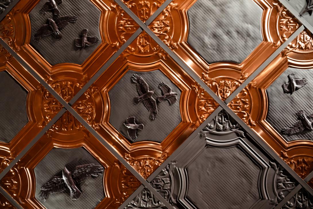 A detail view of pressed tin and copper tiles that form part of a larger artwork