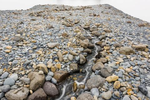 This photograph depicts an entire 'riverbed' installed in a gallery space, complete with running water.