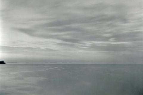 A greyscale photo of the ocean, with the horizon line about two-thirds of the way down the composition.