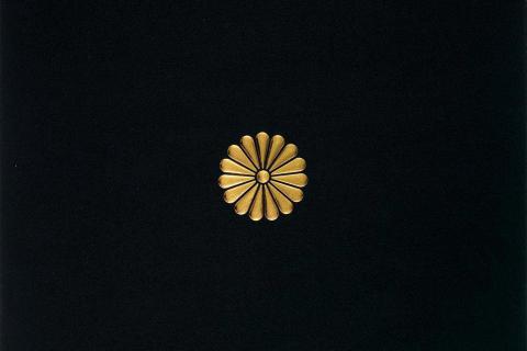 A detail view of a work of art with a small gold flower symbol on a black background.