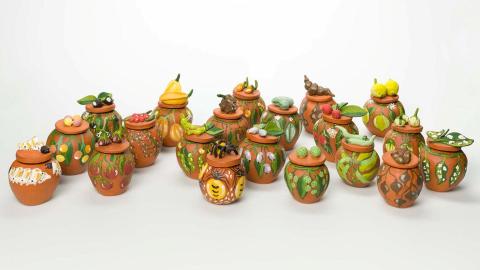 An installation view of many colourful earthenware pots on a white background.