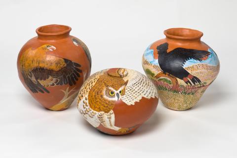 Three earthenware pots by with eagles and owls painted on them.
